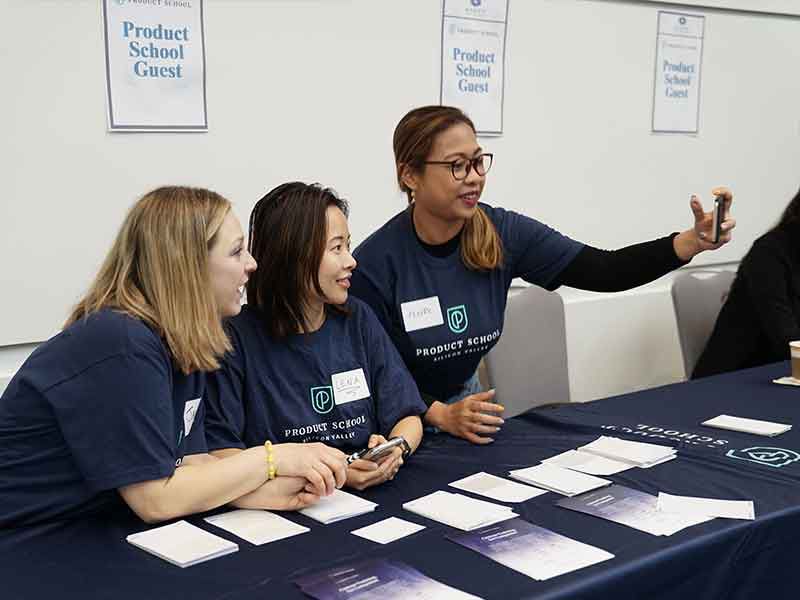 female students take a picture of themselves at the conference booth